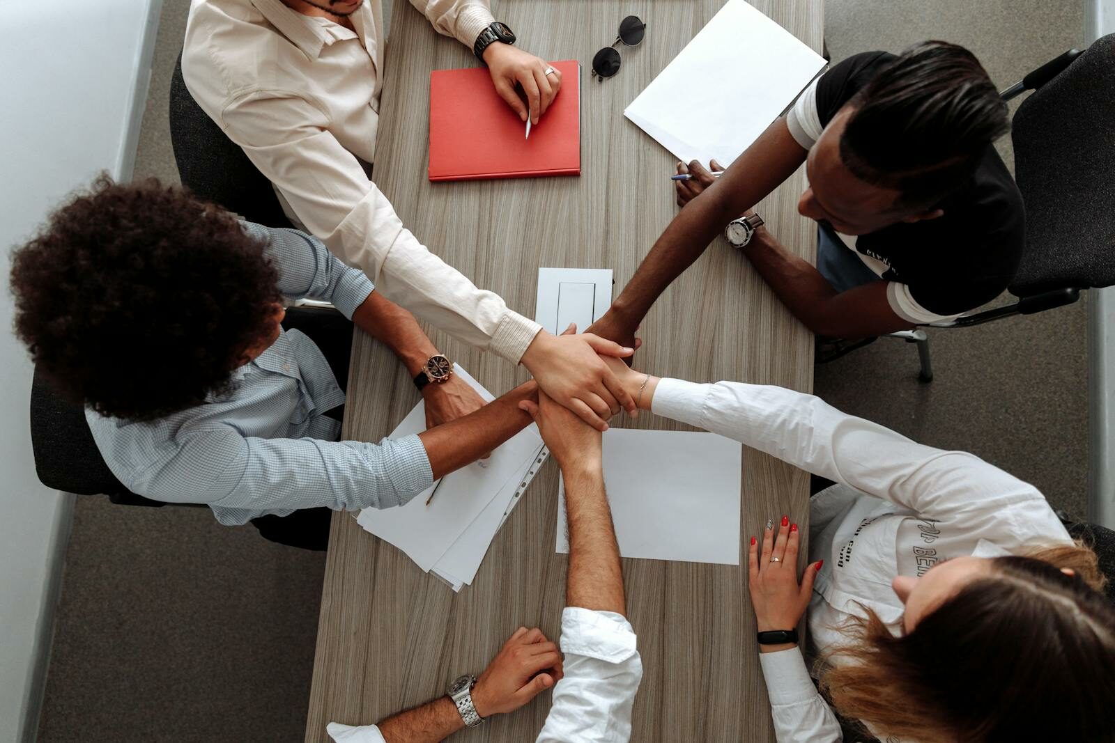 Photo by Thirdman Overhead view of a diverse team placing hands together in a sign of unity during a meeting.